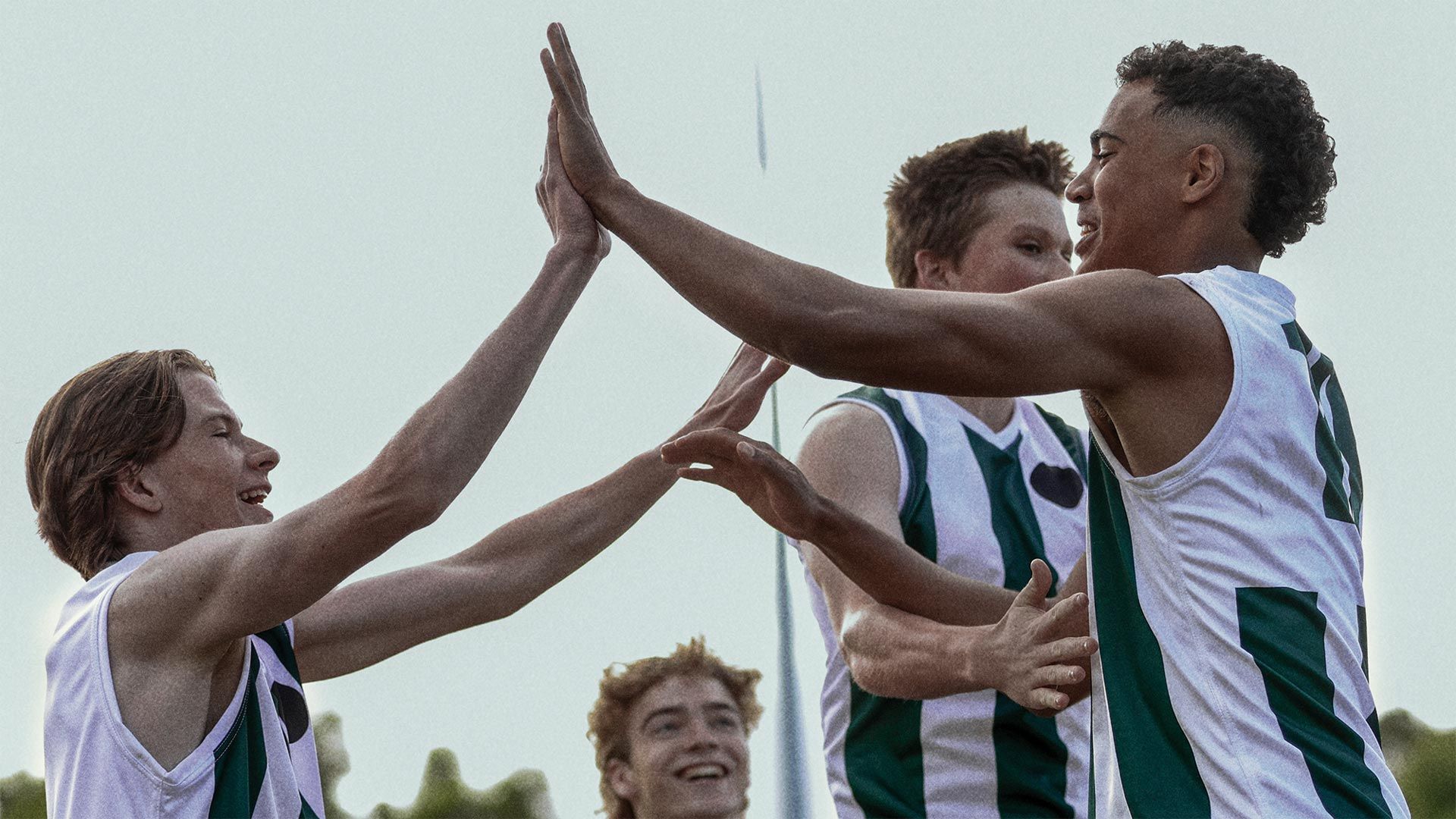 Two young male football players high-fiving.