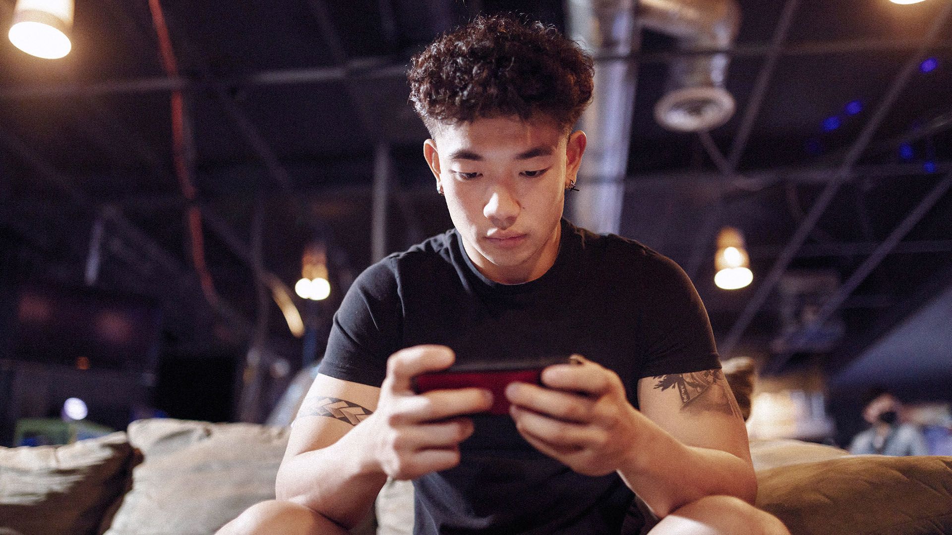 Photo of seated young man, busy on his smartphone.
