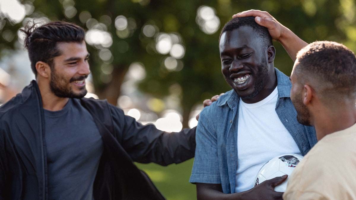 Photo of three smiling men in a park.