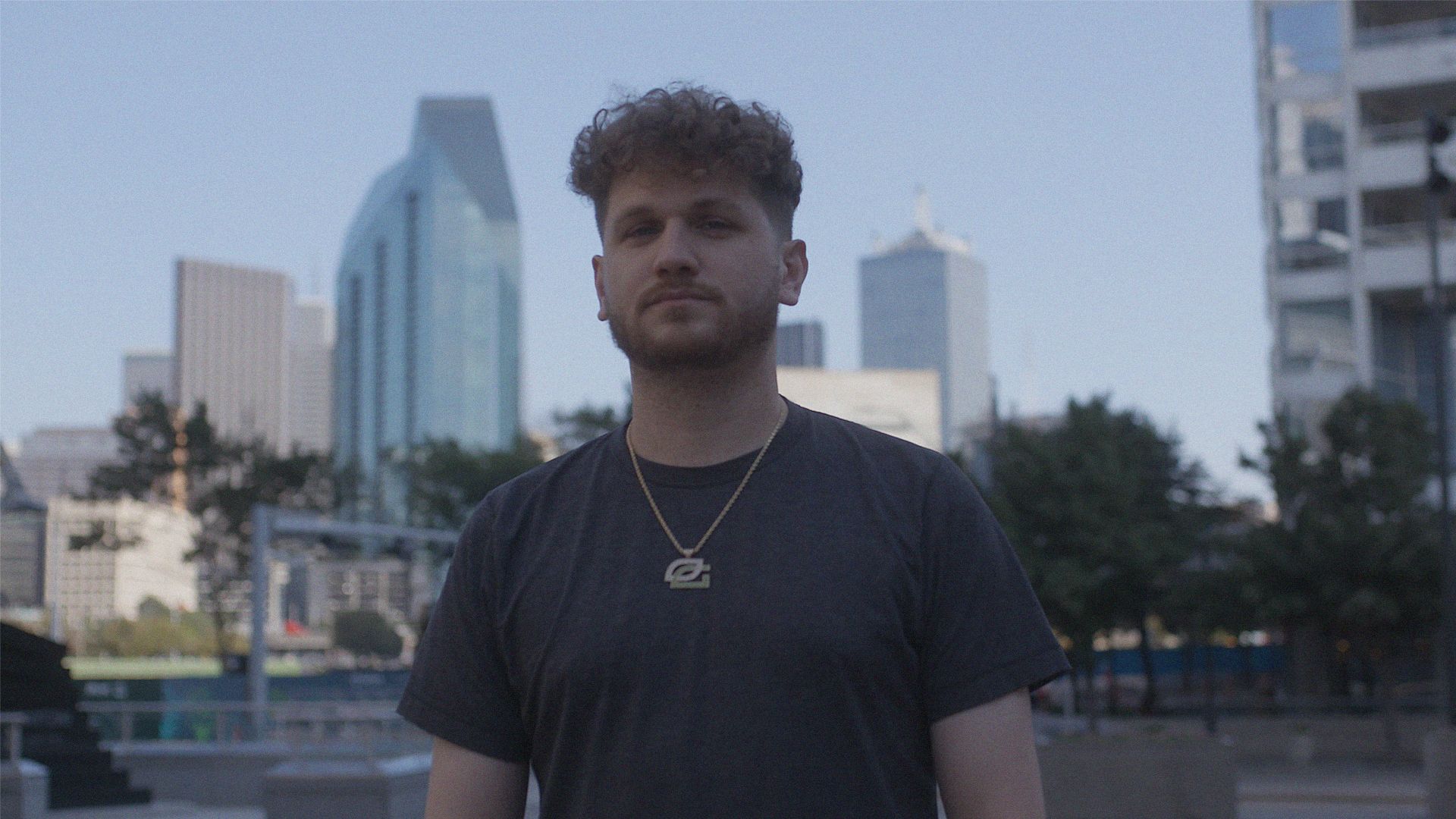 Portrait photo of young man, looking to camera with a city background.